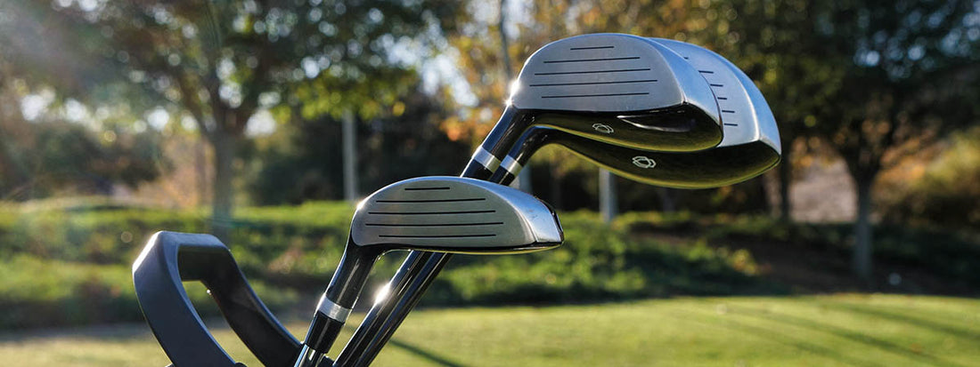 Two golf clubs on a grassy field with trees in the background