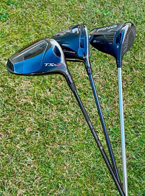 Three golf driver clubs on a grassy background