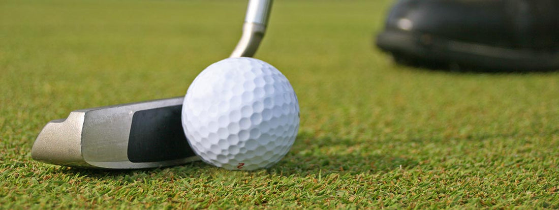 Golf putter and ball on a green golf course