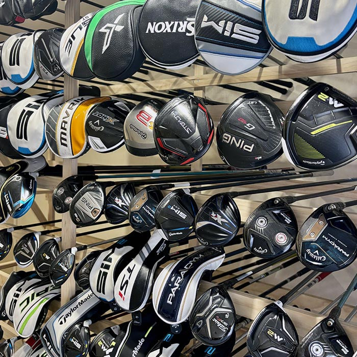 Collection of golf club heads with various brands displayed on a rack.