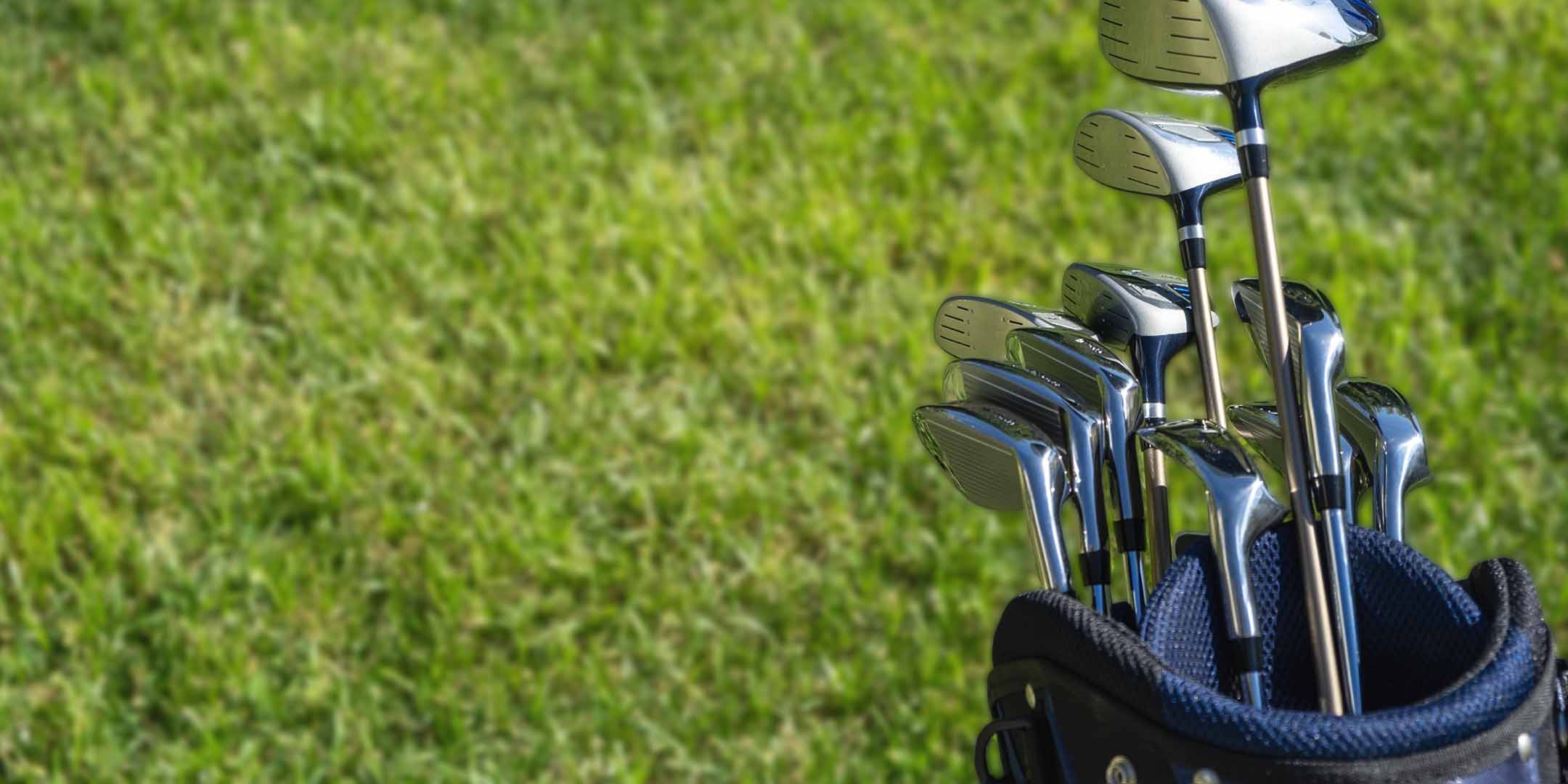 Set of golf clubs in a blue bag on a grassy background