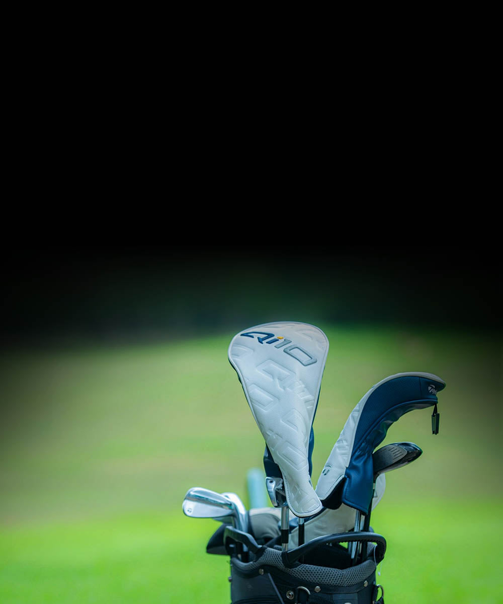 Golf clubs in a bag on a golf course with a blurred background