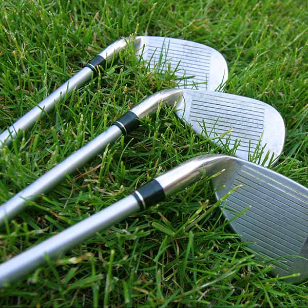 Three golf clubs lying on grass