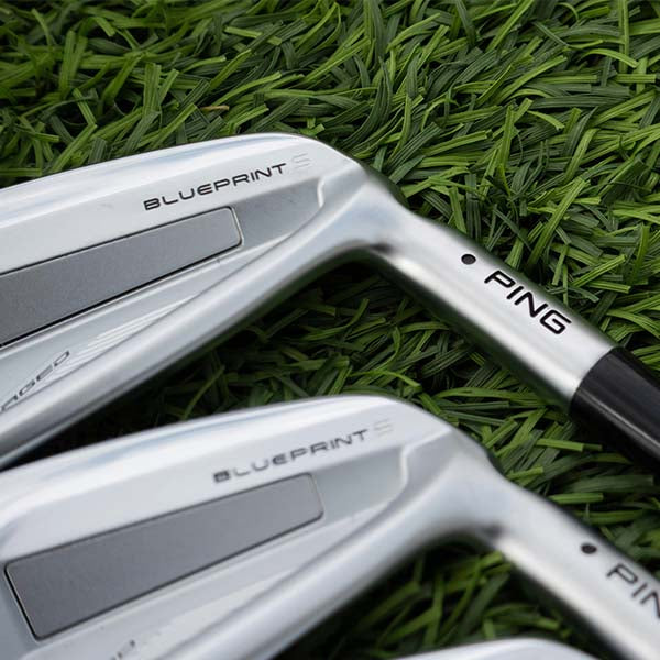 Two golf clubs with 'PING' branding on a grass background