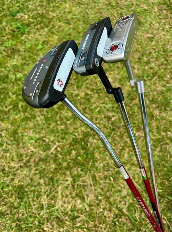 Three golf putters on a grassy background