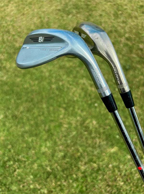 Two golf wedges on a grassy background