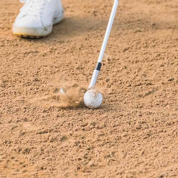 Golf club hitting a golf ball out of a sand trap