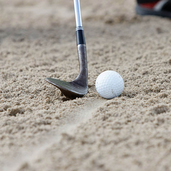 Golf ball and club in sand on a golf course