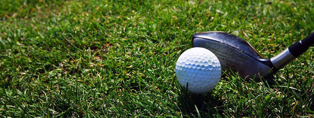 Golf ball and hybrid golf club on a grassy surface