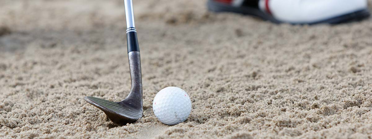 Golf ball and club in sand on a golf course