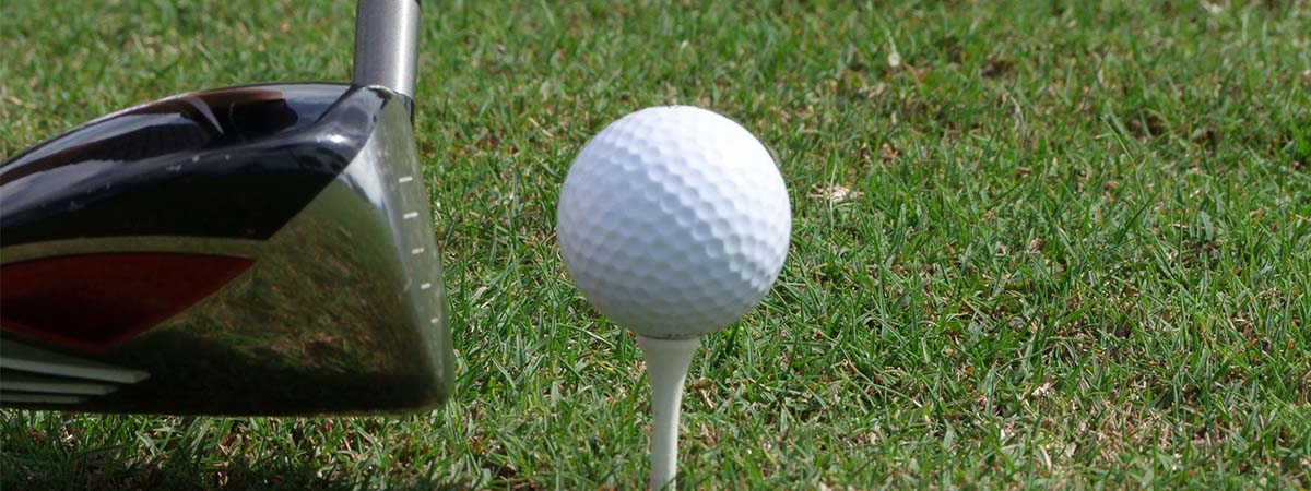 Golf club, golf ball, and tee on grass