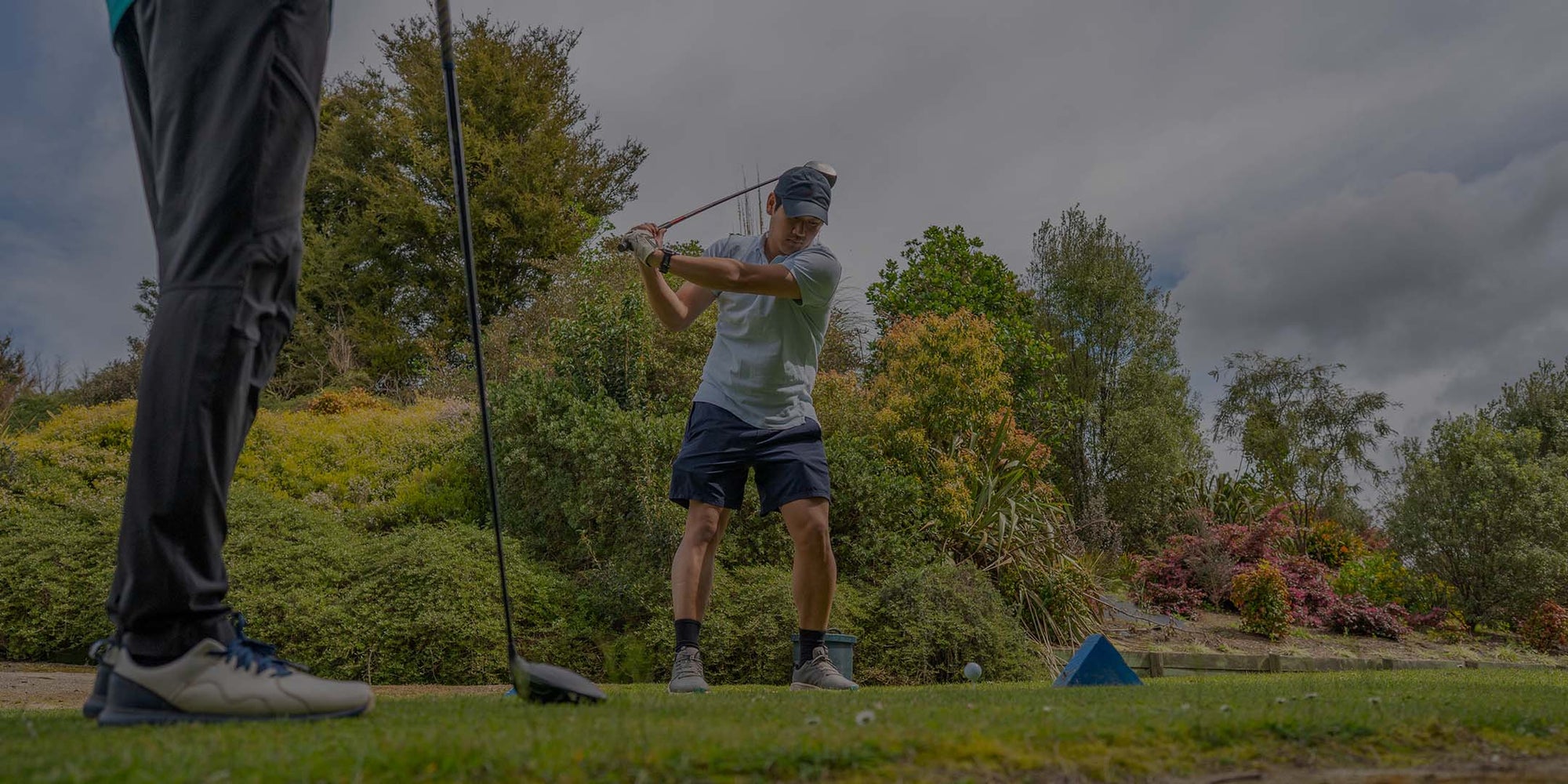 Golfer in action on a golf course with trees and sky in the background